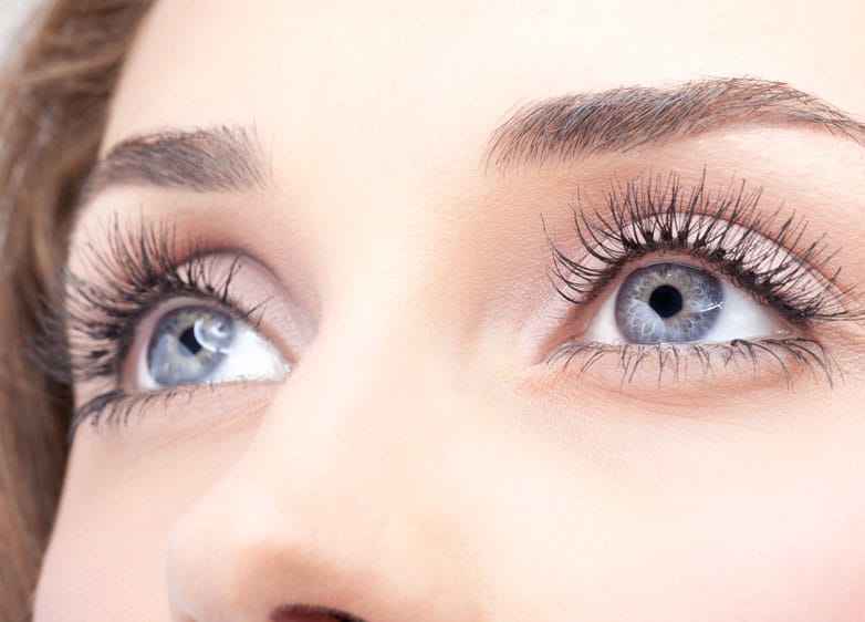 close up of woman's eyes as she stares upward with her hair in the background