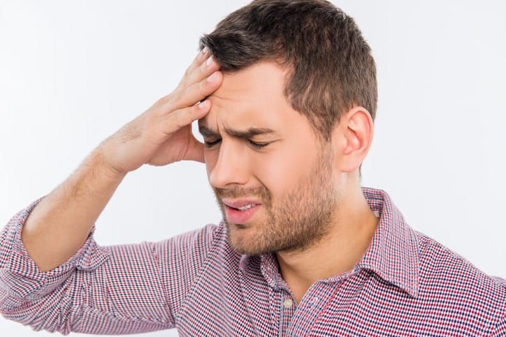 A man having a Blepharospasm, hes holding his head in pain