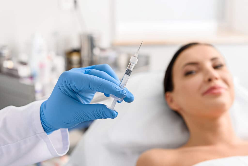 Woman laying down with a doctor preparing a facial injection