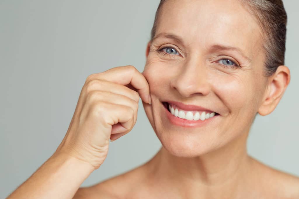 Middle aged woman pinching loose skin on her cheeks