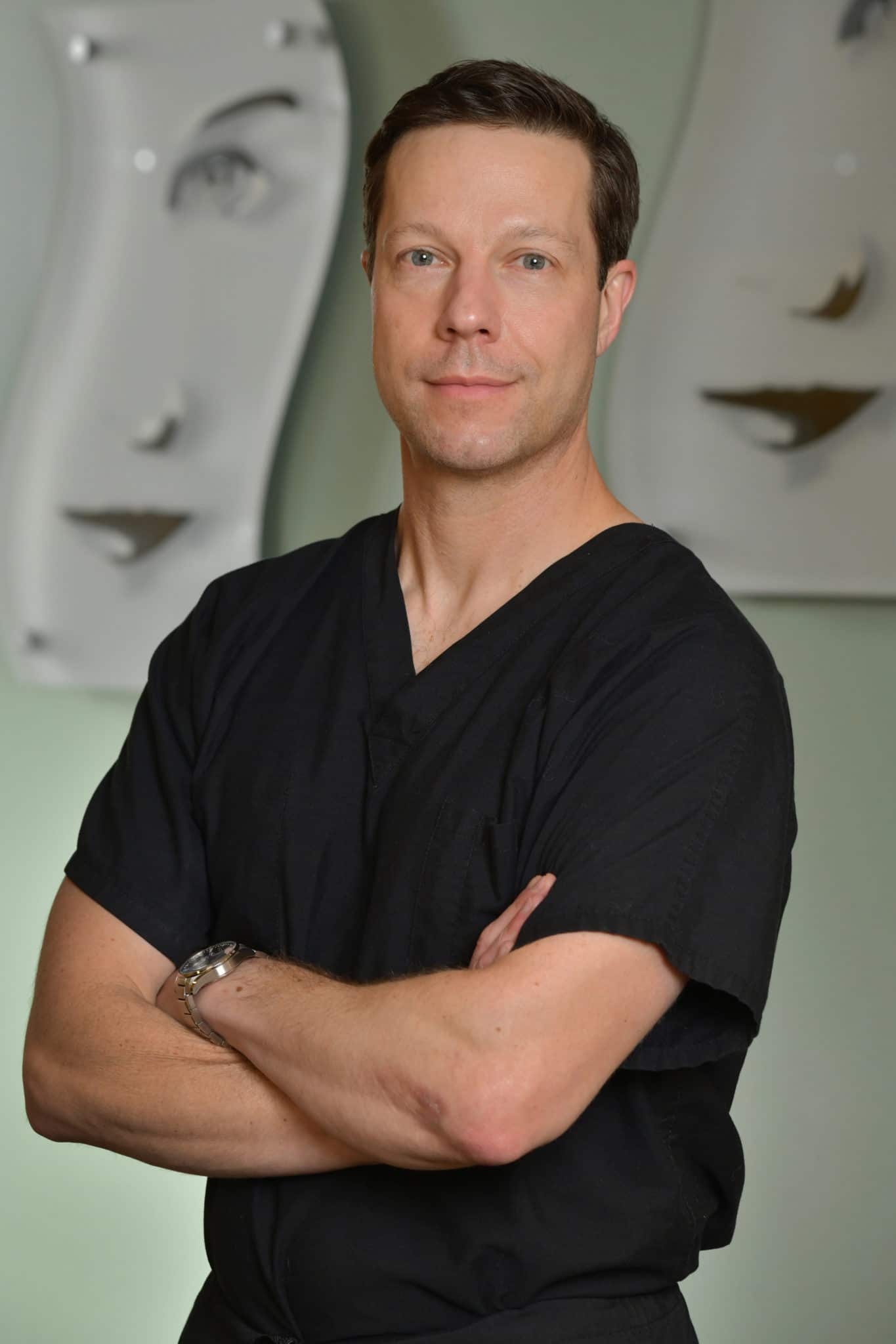 Headshot of male doctor smiling and folding arms in a relaxed manner