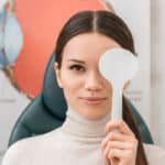 obscured view of young female patient getting eye test in clinic