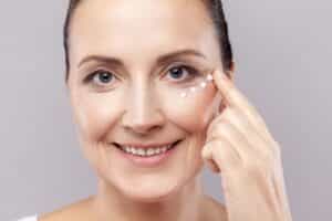 portrait of charming relaxed middle aged woman applies face cream