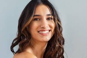 Smiling young woman looking at camera isolated on gray background