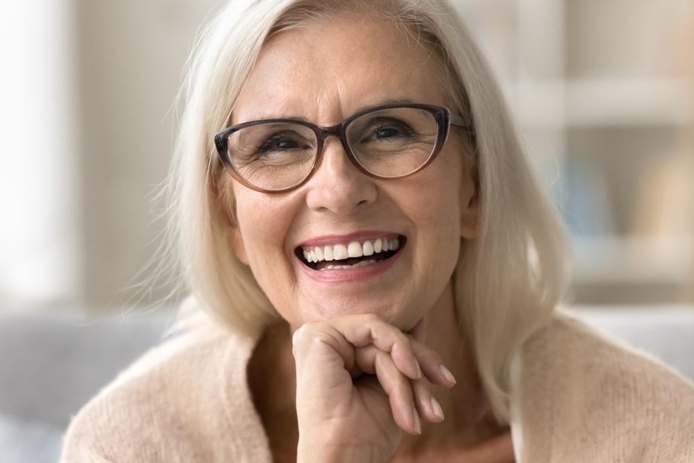 A woman with glasses smiling after ectropion repair