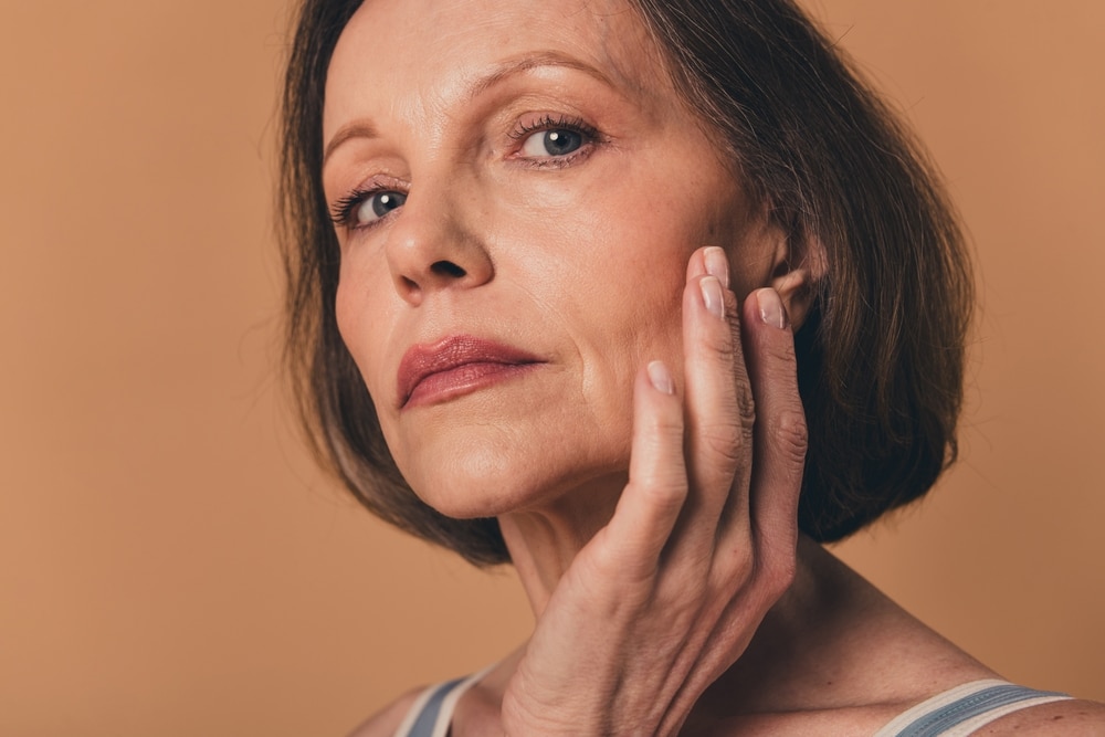 A woman touching her cheek and considering a midface lift in St. Louis